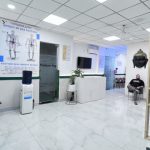 A modern physiotherapy clinic in Gurugram featuring a clean and spacious waiting area with comfortable seating. The decor includes educational posters on posture, Buddha sculptures, and a partition with plants. A patient is seated in the waiting area, creating a serene and welcoming atmosphere.