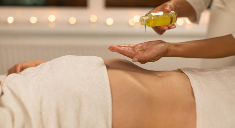Person receiving warm oil therapy on the abdomen, representing an Ayurvedic belly button oiling detox ritual